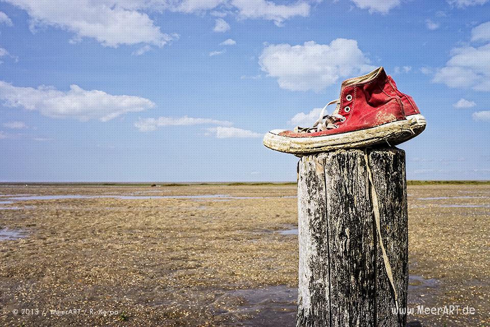 Zurückgelassene Sneaker auf einem Holzpfahl am Strand // Foto: R. Kerpa