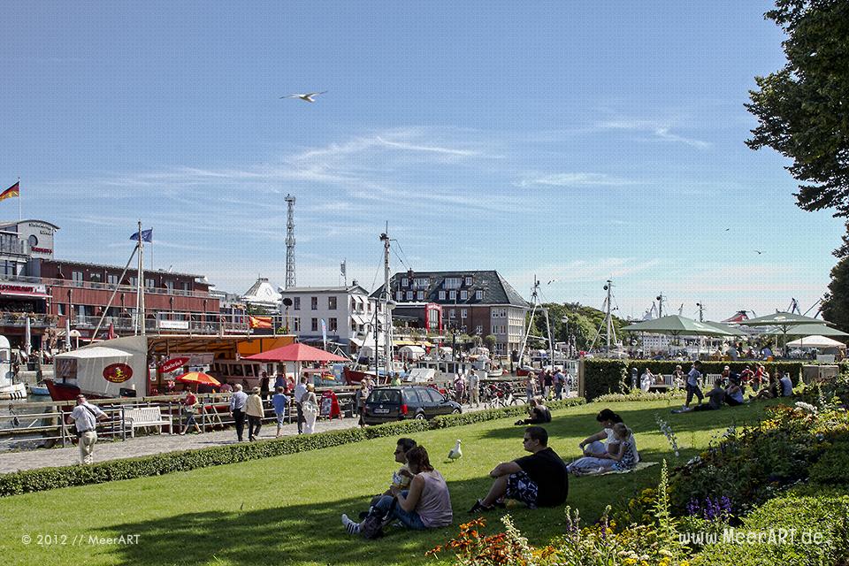 Touristen genießen das sommerliche Wetter auf der Promenade im Hafen von Warnemünde // Foto: MeerART