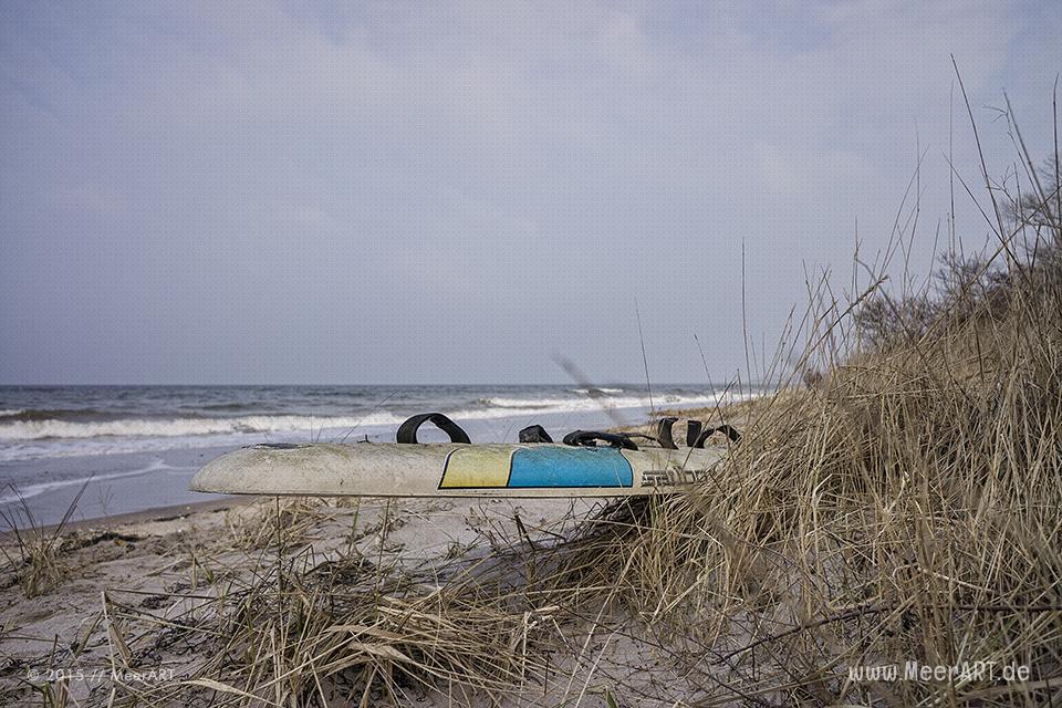 Eine angespültes Surfbrett an einem Strandabschnitt auf der Halbinsel Priwall // Foto: MeerART